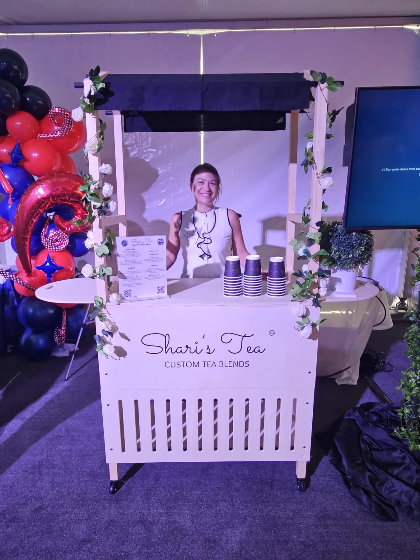 Branded Shari's Tea custom-blends cart with red, white and blue balloons at a Delta brand activation