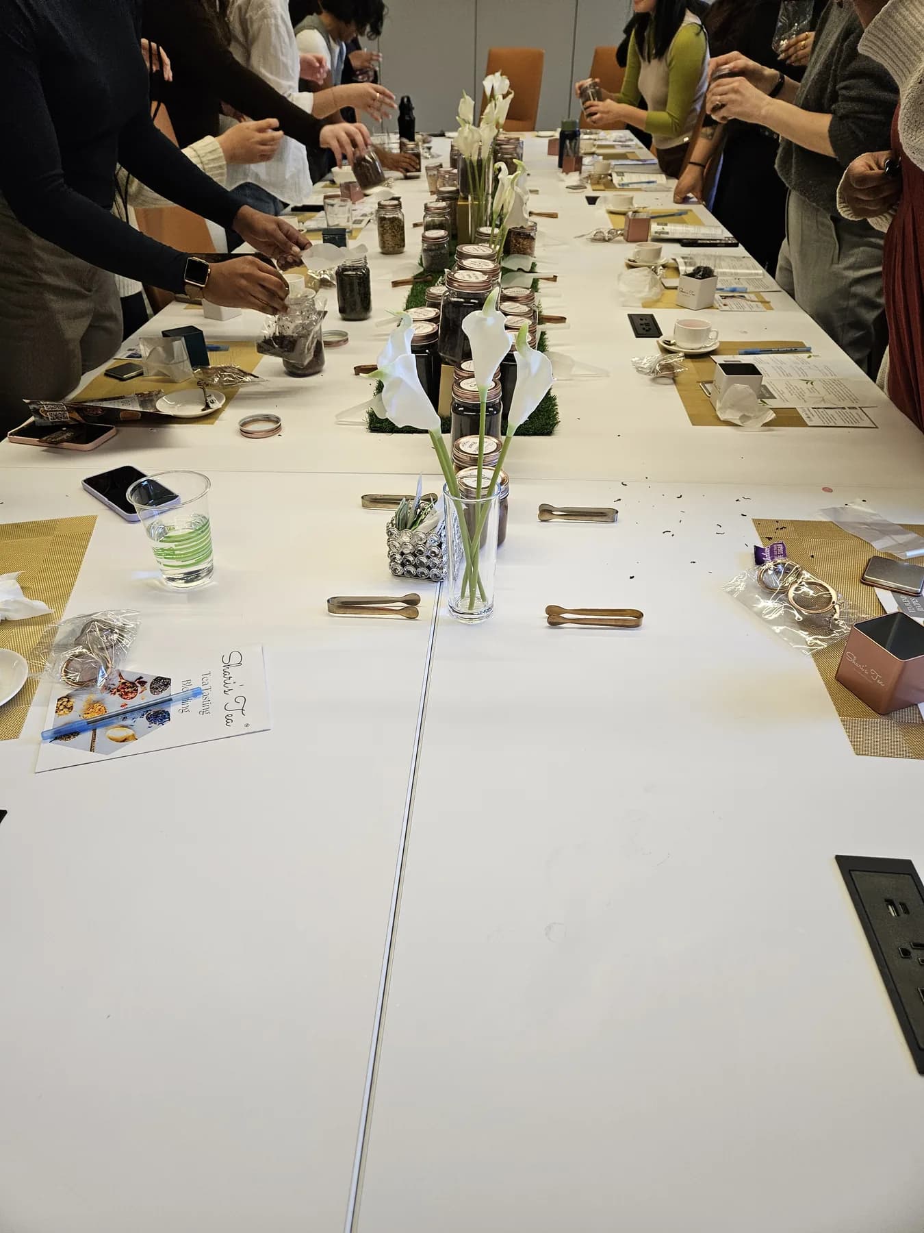 Guests blending their own custom tea at a long tasting table during an interactive event